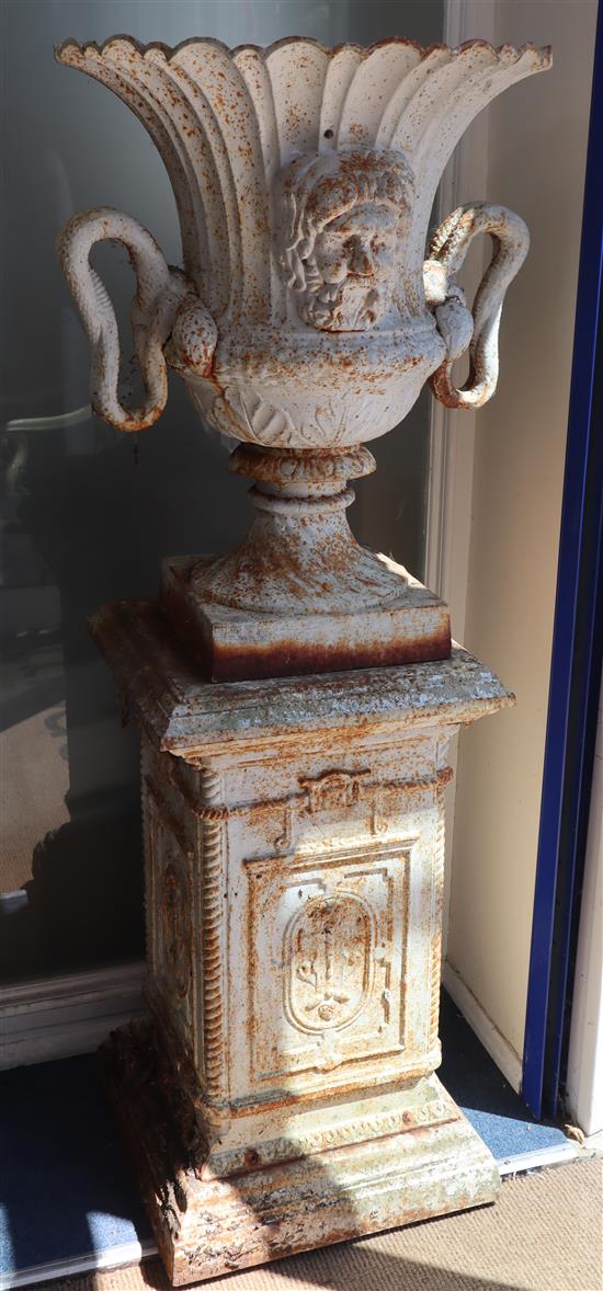 A pair of white campana cast iron garden urns on square plinths H.155cm